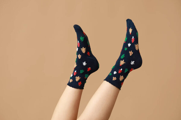 Legs of young woman in black Christmas socks on beige background