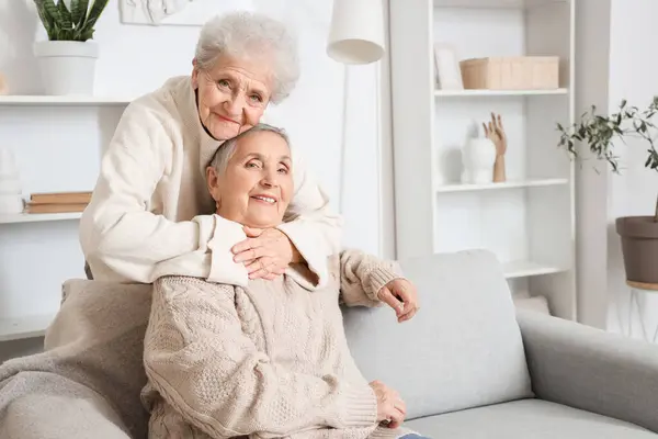 stock image Senior woman hugging her friend on sofa at home