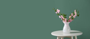 Masanın üzerinde yeşil arkaplan ve metin için yeri olan güzel dalları olan vazo. Merhaba bahar.