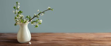 Masanın üzerinde, gri arkaplanı ve yazı için yeri olan güzel dalları olan vazo. Merhaba bahar.