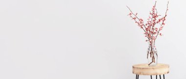 Masanın üzerinde güzel dallar açan bir vazo. Arka planda ışık ve metin için yer var. Merhaba bahar.