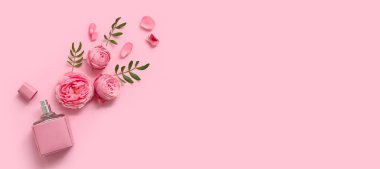 Parfüm şişesi ve pembe arka planda gül çiçekleri.