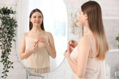 Sivilceli genç bir kadın ve banyoda aynanın yanında serum.