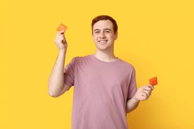 Sarı arka planda prezervatifli genç bir adam. Güvenli seks konsepti