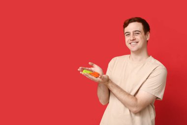 Kırmızı arka planda prezervatifli genç bir adam. Güvenli seks konsepti