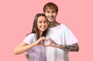 Pembe arka planda el ele tutuşan genç çift