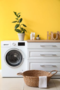 Çamaşır sepetinin, çamaşır makinesinin ve tezgahın olduğu odanın içinde.