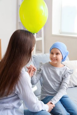 Mavi balonla kemoterapiden sonra küçük bir kız ve annesi evde. Uluslararası Çocukluk Kanser Günü
