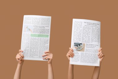 Kahverengi arka planda gazeteleri olan kadınlar