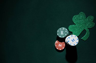 Koyu yeşil arka planda şanslı yoncalı poker fişleri. Aziz Patrick Günü kutlaması