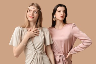 Kahverengi arka planda farklı takılara sahip güzel genç kadınlar.