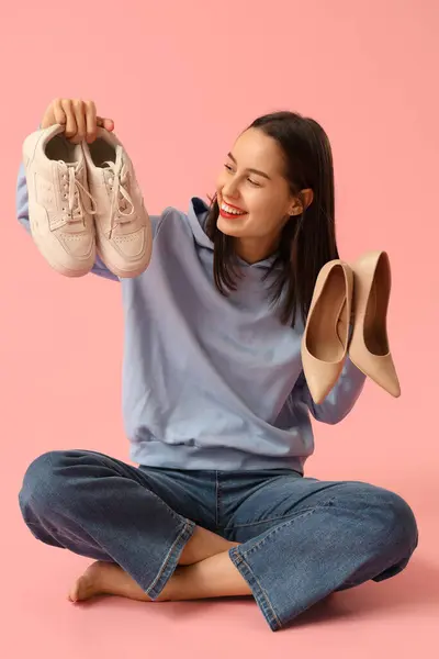 Glad Ung Kvinna Väljer Sneakers Över Högklackade Skor Rosa Bakgrund — Stockfoto