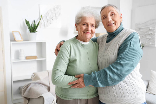 Senior female friends hugging at home