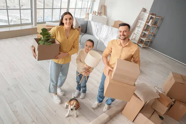 Happy family with belongings and Beagle dog in room on moving day
