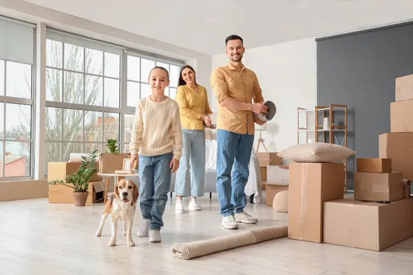Happy family with rolled carpet and Beagle dog in room on moving day