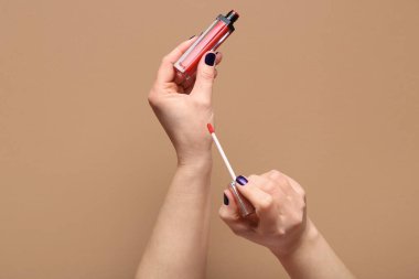 Kahverengi arka planda kırmızı sıvı ruj olan kadın elleri.