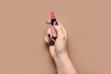 Kahverengi arka planda pembe ruj olan bir kadın eli.