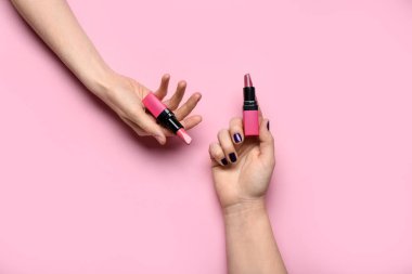 Pembe arka planda ruj izi olan kadın elleri.