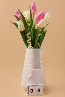 Kahverengi arka planda güzel laleleri ve küp takvimi olan vazo. Uluslararası Kadınlar Günü
