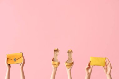 Sarı topuklu ve pembe çantalı kadınlar.