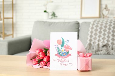 Kutlama kartı, bir buket lale ve Anneler Günü hediyesi oturma odasında masada.