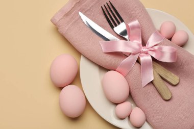 Paskalya yumurtaları, peçete ve bej arka planda çatal bıçak seti ile güzel bir masa.
