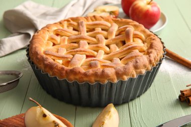 Lezzetli ev yapımı elmalı turta ve yeşil ahşap arka planda meyveler.