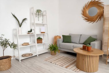 Rafları, çiçekleri, aynası, masası ve kanepesi olan şık bir oturma odası.