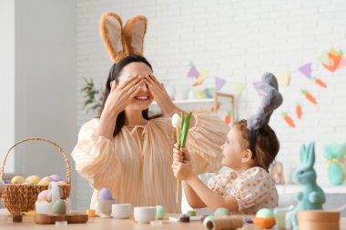 Paskalya tavşanı kulaklı mutlu genç kadın kızından lale alıyor.