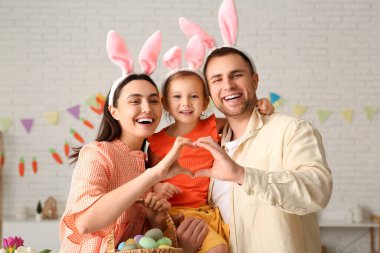 Paskalya tavşanı kulaklarındaki mutlu aile evde elleriyle kalp yapıyor.