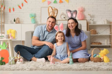 Tavşan kulaklı mutlu aile Paskalya hediyeleri evde yerde oturuyor.
