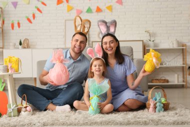 Tavşan kulaklı mutlu aile Paskalya hediyeleri evde yerde oturuyor.