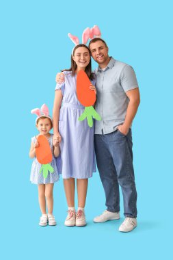Paskalya tavşanı kulaklı mutlu aile mavi arka planda kağıt havuç