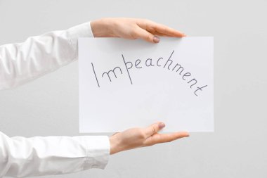 Beyaz arka planda IMPEACHMENT pankart posteri tutan kadın