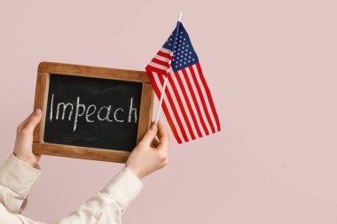 Pembe arka planda IMPEACH ve ABD bayrağı olan yazı tahtası tutan kadın.