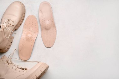 Beyaz arka planda çizmeler ve deri ortopedik tabanlar