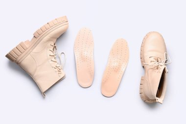 Çizmeler ve deri ortopedik tabanlar beyaz arka planda izole edilmiş.