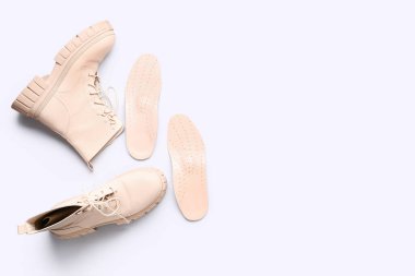 Çizmeler ve deri ortopedik tabanlar beyaz arka planda izole edilmiş.