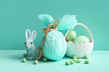 Paskalya yumurtalı seramik sepet ve turkuaz arka planda oyuncak tavşan.