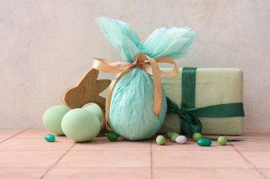 Kağıda sarılmış Paskalya yumurtaları ve pembe fayans üzerinde hediye kutusu.