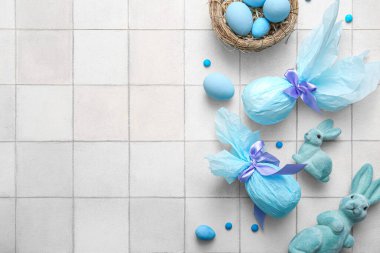 Kağıda sarılmış boyanmış Paskalya yumurtaları ve beyaz fayanslı oyuncak tavşancıklar.