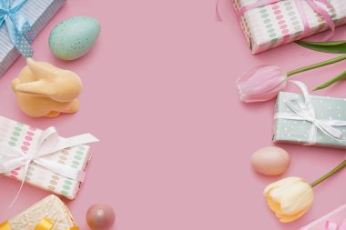 Üzüntülü Paskalya yumurtalarından yapılmış çerçeve hediye kutuları, oyuncak tavşan ve pembe arka planda lale çiçekleri