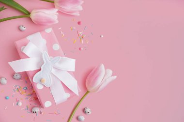Lale çiçekli hediye kutusu ve pembe arka planda Paskalya oyuncak tavşanı.