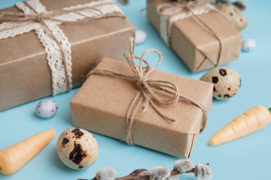 Easter gift boxes with eggs and branch of pussy willow on blue background
