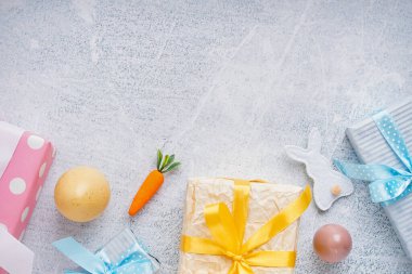 Hediye kutularıyla boyanmış Paskalya yumurtaları ve beyaz grunge arka planda oyuncak tavşancık.