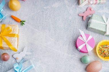 Hediye kutularıyla boyanmış Paskalya yumurtalarından yapılmış çerçeveler ve beyaz grunge arka planda oyuncak tavşanlar.