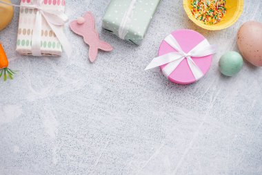Hediye kutularıyla boyanmış Paskalya yumurtaları ve beyaz grunge arka planda oyuncak tavşancık.