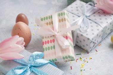 Hediye kutularıyla boyanmış Paskalya yumurtaları ve beyaz grunge arka planda lale çiçeği.