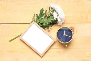 Çerçeveli çalar saat ve ahşap arka planda kasımpatı çiçekleri