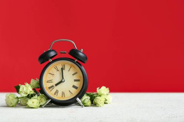 Beyaz masadaki gül çiçekleri ve çalar saat